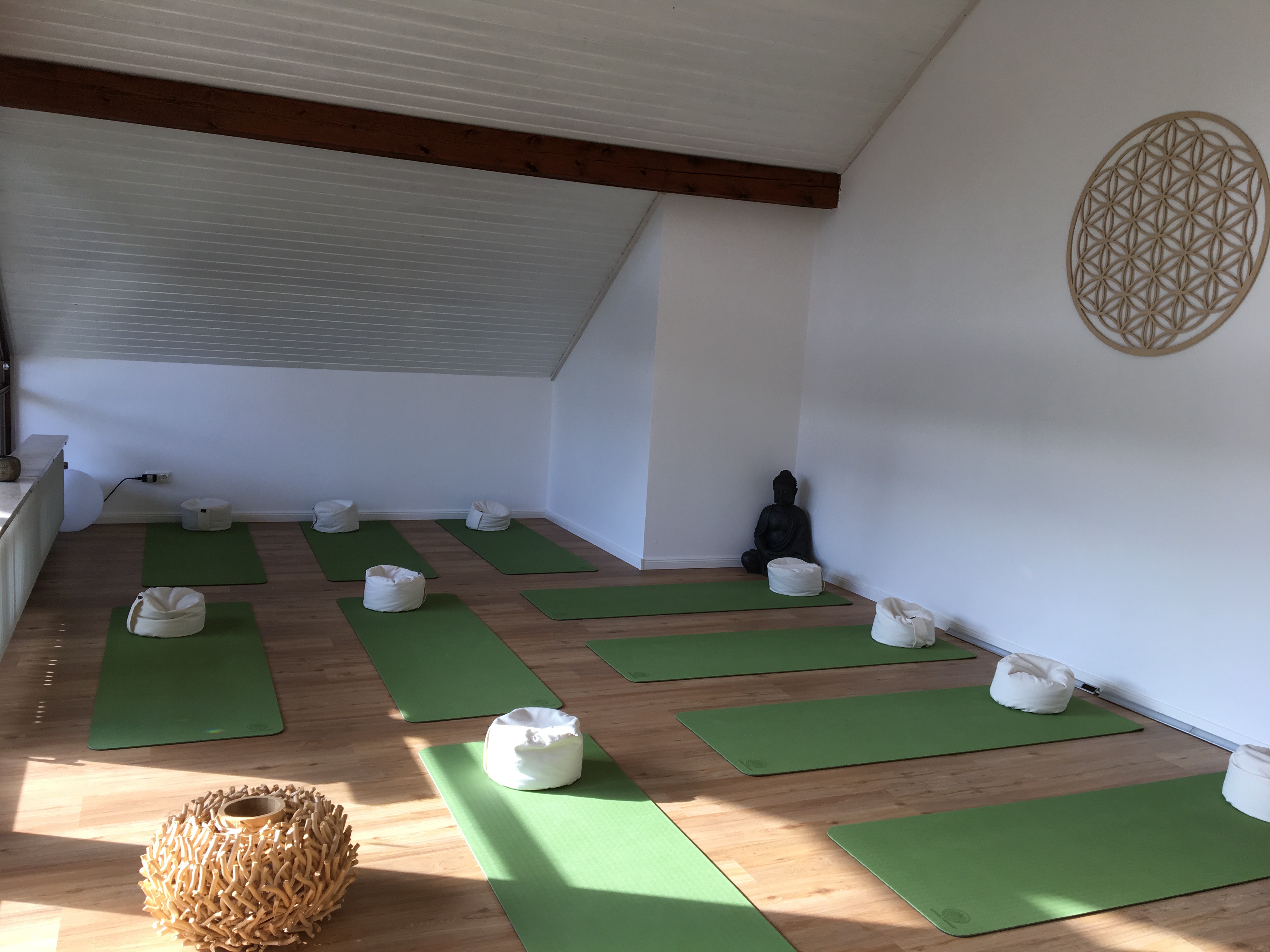 Yoga-Studio mit grünen Matten und Blume des Lebens an der Wand